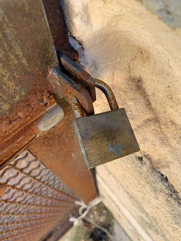 Rostiges Vorhängeschloss am Metallzwinger